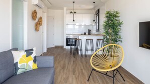 Una cocina moderna con gabinetes blancos, una isla central y taburetes de bar.
