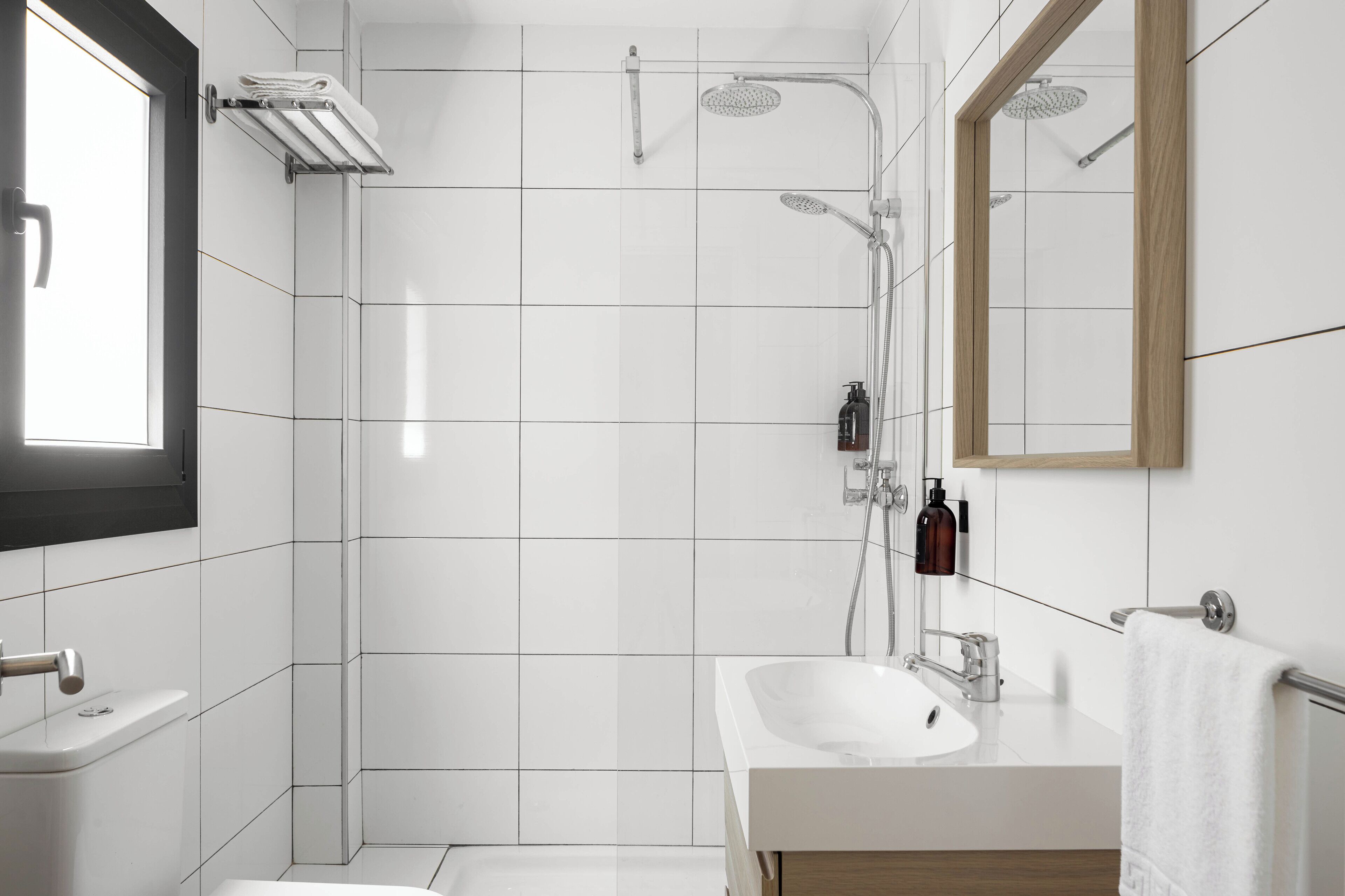 A modern bathroom with a white sink, mirror, and shower.