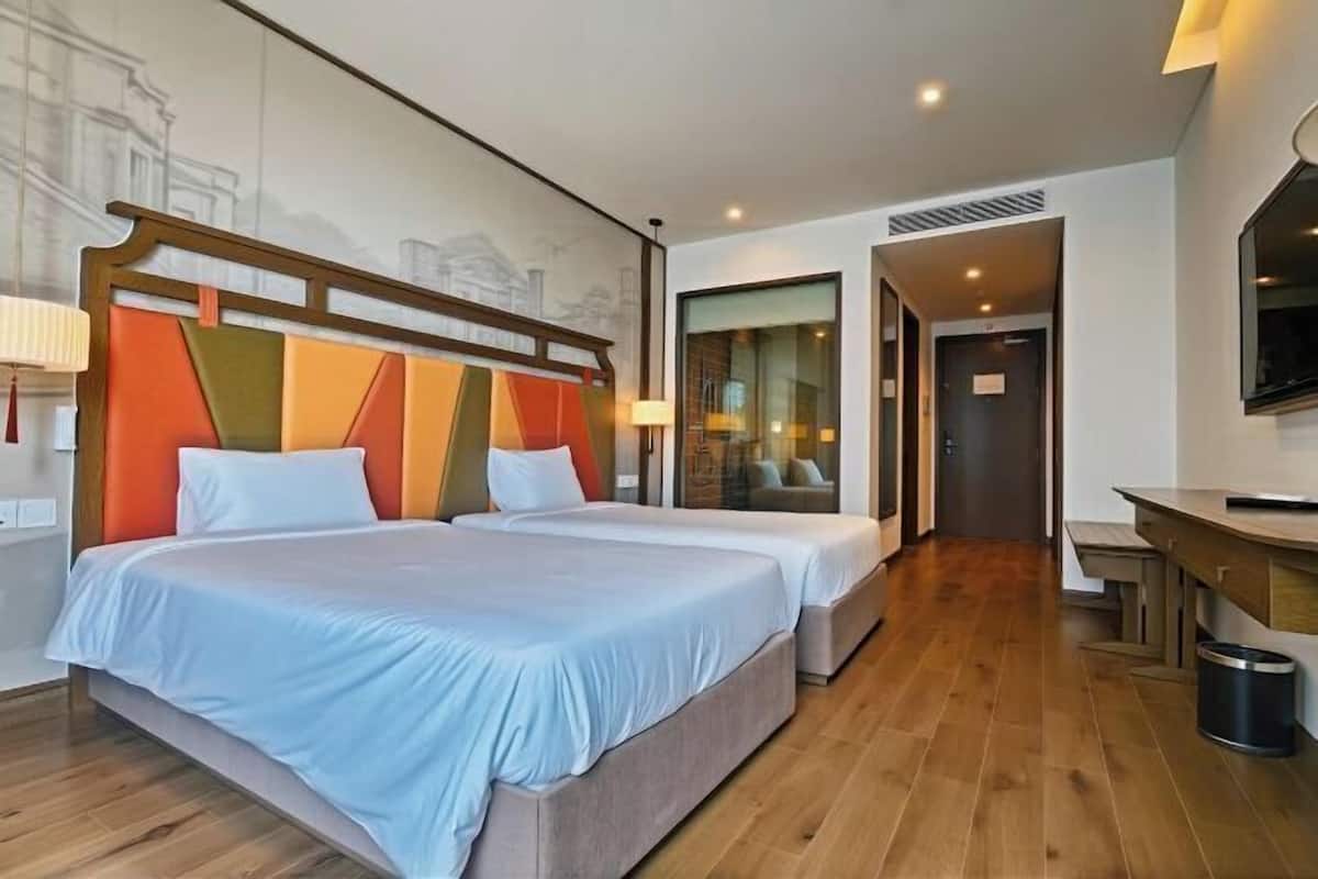 Une chambre d’hôtel avec deux lits, un plancher en bois, un bureau et une télévision.