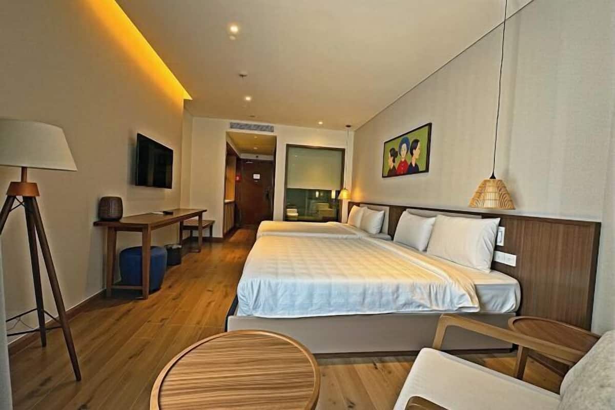 Une chambre d’hôtel avec deux lits, un bureau, une chaise et une table ronde.