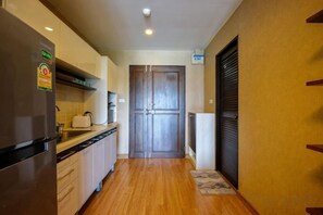A narrow kitchen with a refrigerator, a double door, and a wooden floor. - Luxury Living in heart of Nimman (Chiang Mai)