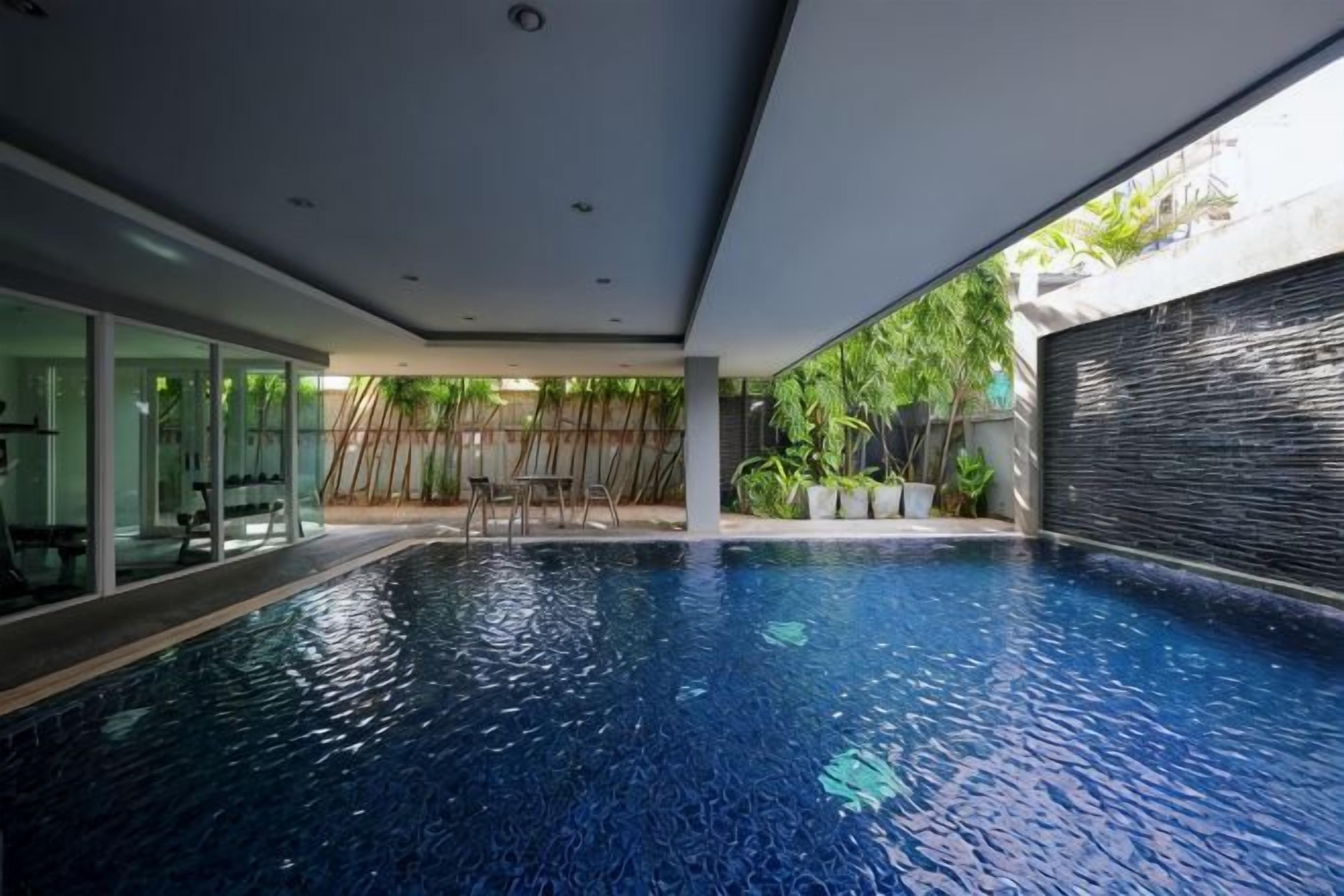 An indoor swimming pool with clear water, surrounded by glass walls and a modern ceiling.