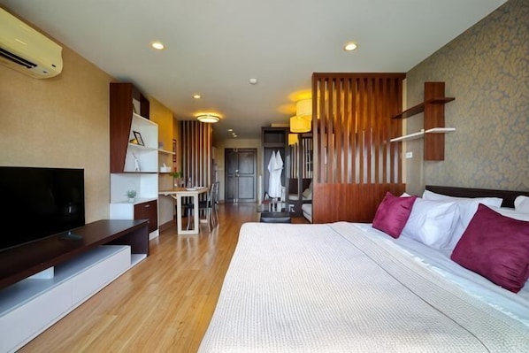 A hotel room with a large bed, a TV, a desk, and a wardrobe.