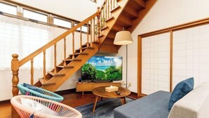 A living room with a wooden staircase, a television, and modern furniture. - Mizunowa (Nago)