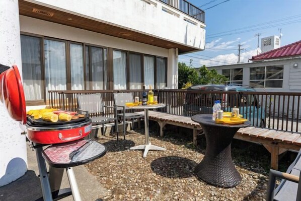 An outdoor patio with a grill, seating, and a table with drinks. - Mizunowa (Nago)