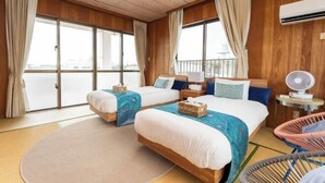A hotel room with two beds, a view through large windows, a fan, and a chair. - Mizunowa (Nago)