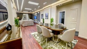 A modern dining area with a round table, white chairs, and a glass-top table. - RD The Residence Serviced Apartment, New Cairo Prime Location (New Cairo City)