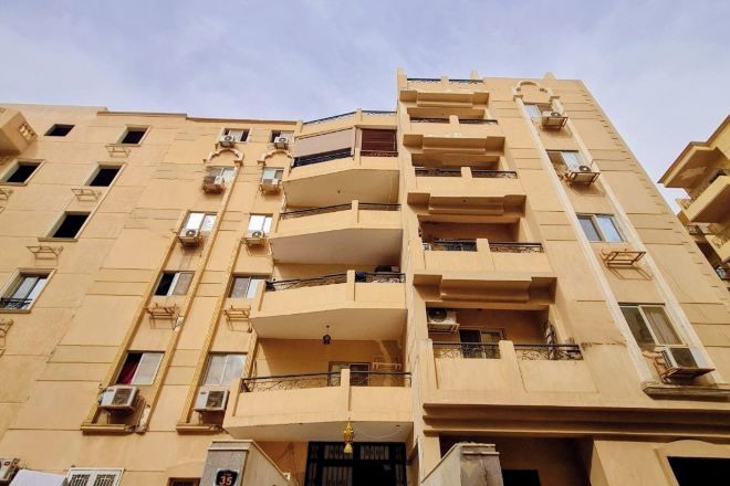 Un edificio de varios pisos con balcones, unidades de aire acondicionado y un cartel que indica el número de habitaciones.
