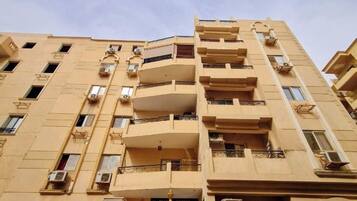 Un edificio de varios pisos con balcones, unidades de aire acondicionado y un cartel que indica el número de habitaciones.