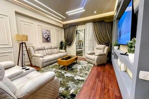 A living room with a sofa, armchairs, a coffee table, and a TV. - RD The Residence Serviced Apartment, New Cairo Prime Location (New Cairo City)
