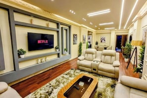 Una sala de estar con televisor de pantalla plana, sillón de cuero y una mesa de centro.