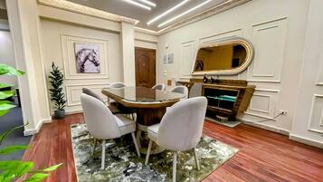 A dining area with a round table, chairs, a rug, and a mirror on the wall.