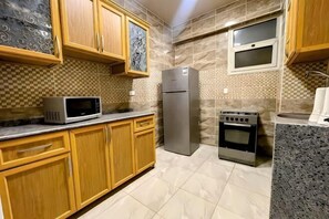 A kitchen with wooden cabinets, a microwave, a refrigerator, and an oven. - RD The Residence Serviced Apartment, New Cairo Prime Location (New Cairo City)