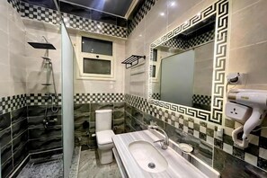 Un baño con piso a cuadros, un espejo grande, un lavamanos y un inodoro.