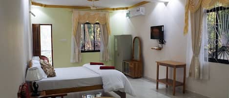 Un dormitorio con una cama, una mesa de madera, un espejo y un televisor.