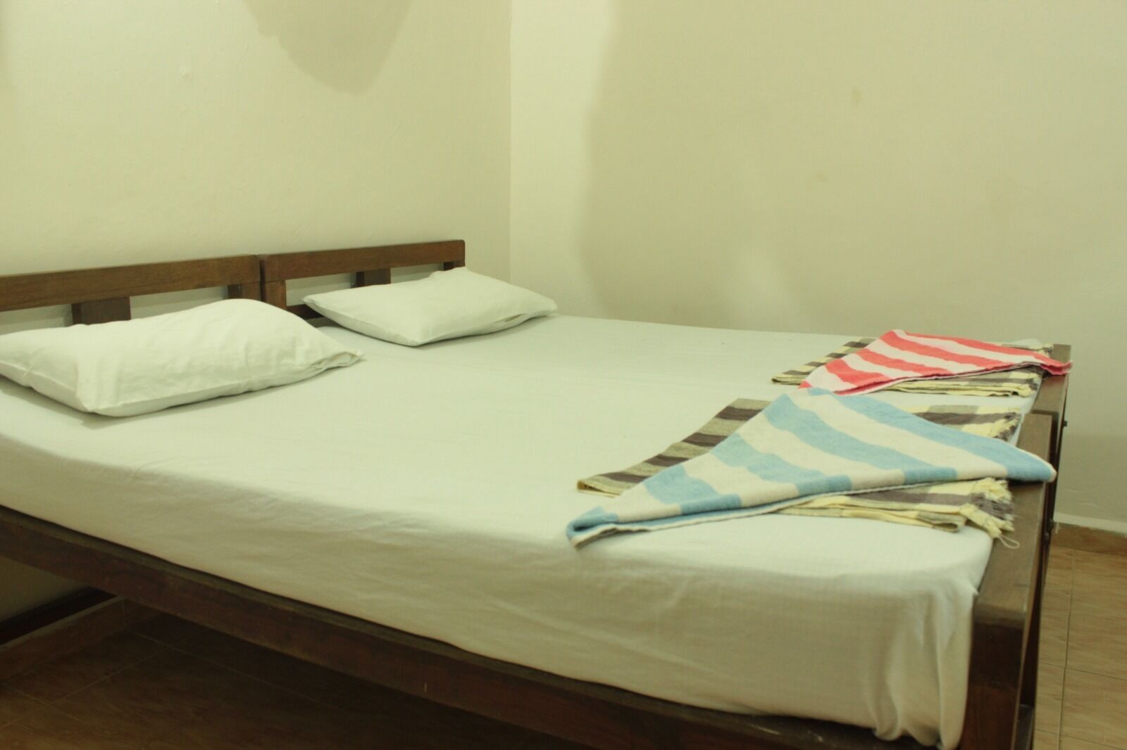 Una cama individual con cabecera de madera, ropa de cama blanca y una colcha a rayas.