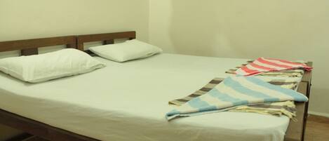 Una cama individual con cabecera de madera, ropa de cama blanca y una colcha a rayas.