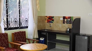 A compact kitchen with a sink, a refrigerator, and a dining area with a table and chairs. - Pritams Cottages (Canacona)