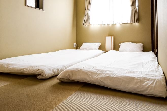 Une chambre avec deux lits simples, une table de chevet et une fenêtre avec des rideaux.