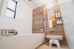 A modern bathroom with a wooden wall, a white sink, a shower, and a toilet. - KIRAKU･KAYA (Kyoto)