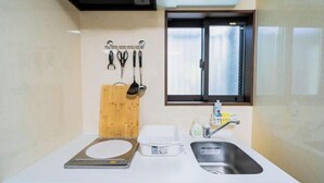 A compact kitchen with a sink, a window, and a wooden cutting board. - KIRAKU･KAYA (Kyoto)
