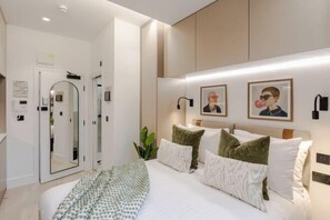 Een moderne hotelkamer met een groot bed, een spiegel, een kledingkast en kunstwerken in lijsten aan de muur.
