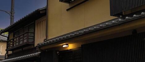 A traditional Japanese building with a wooden balcony and a black gate.