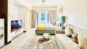 A hotel room with a bed, a sofa, a TV, a coffee table, and a window with curtains. - Gcv1 (Dubai)