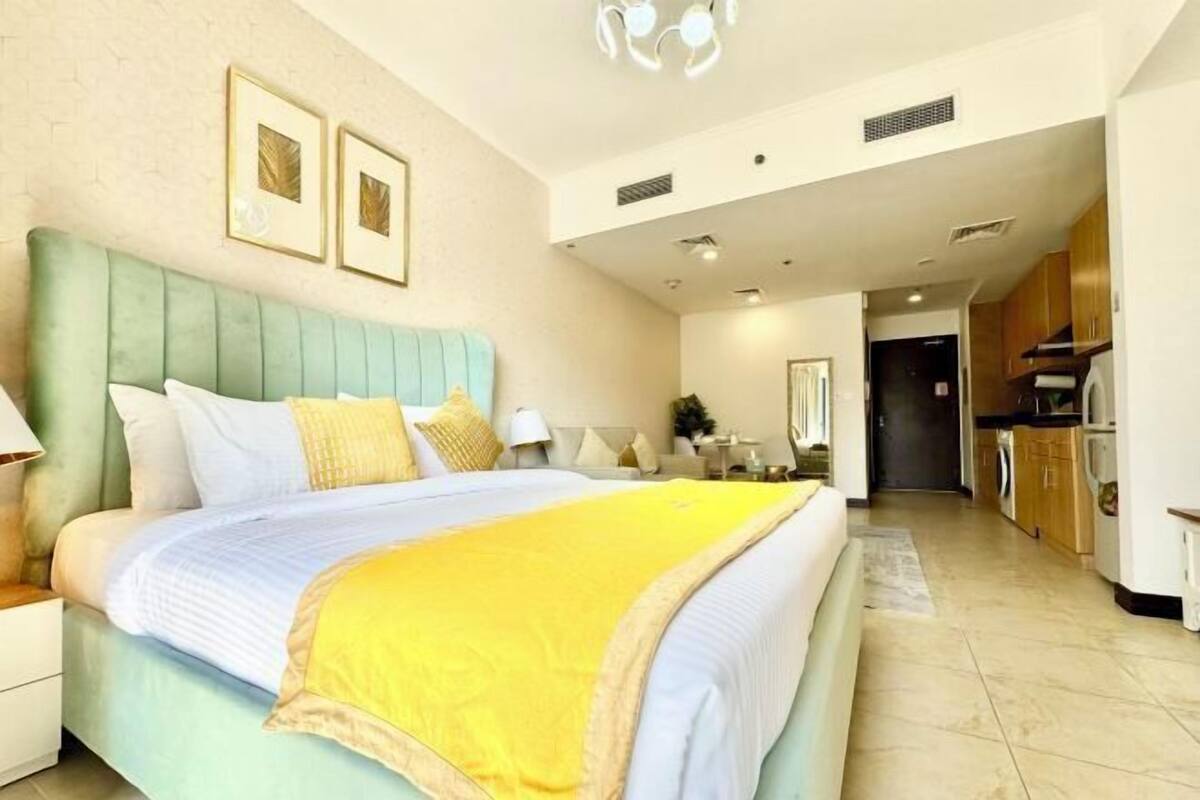 A bedroom with a large bed, a nightstand, a dresser, and a bathroom visible in the background.