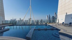 A rooftop pool with a city skyline in the background, surrounded by modern buildings. - Gcv1 (Dubai)