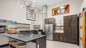 A modern kitchen with a central island, bar stools, a stainless steel refrigerator, and wooden cabinetry. - Downtown•Near River, Trails & Shopping (Salida)