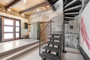 Un interior moderno con una escalera, un banco y una puerta que da a otra habitación.