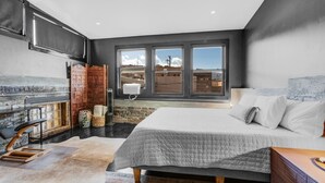 A modern bedroom with a large bed, a fireplace, and a view of the city. - Downtown•Near River, Trails & Shopping (Salida)