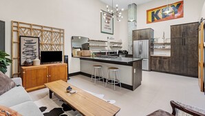 A modern kitchen with a central island, bar stools, and a large mirror above the island. - Downtown•Near River, Trails & Shopping (Salida)