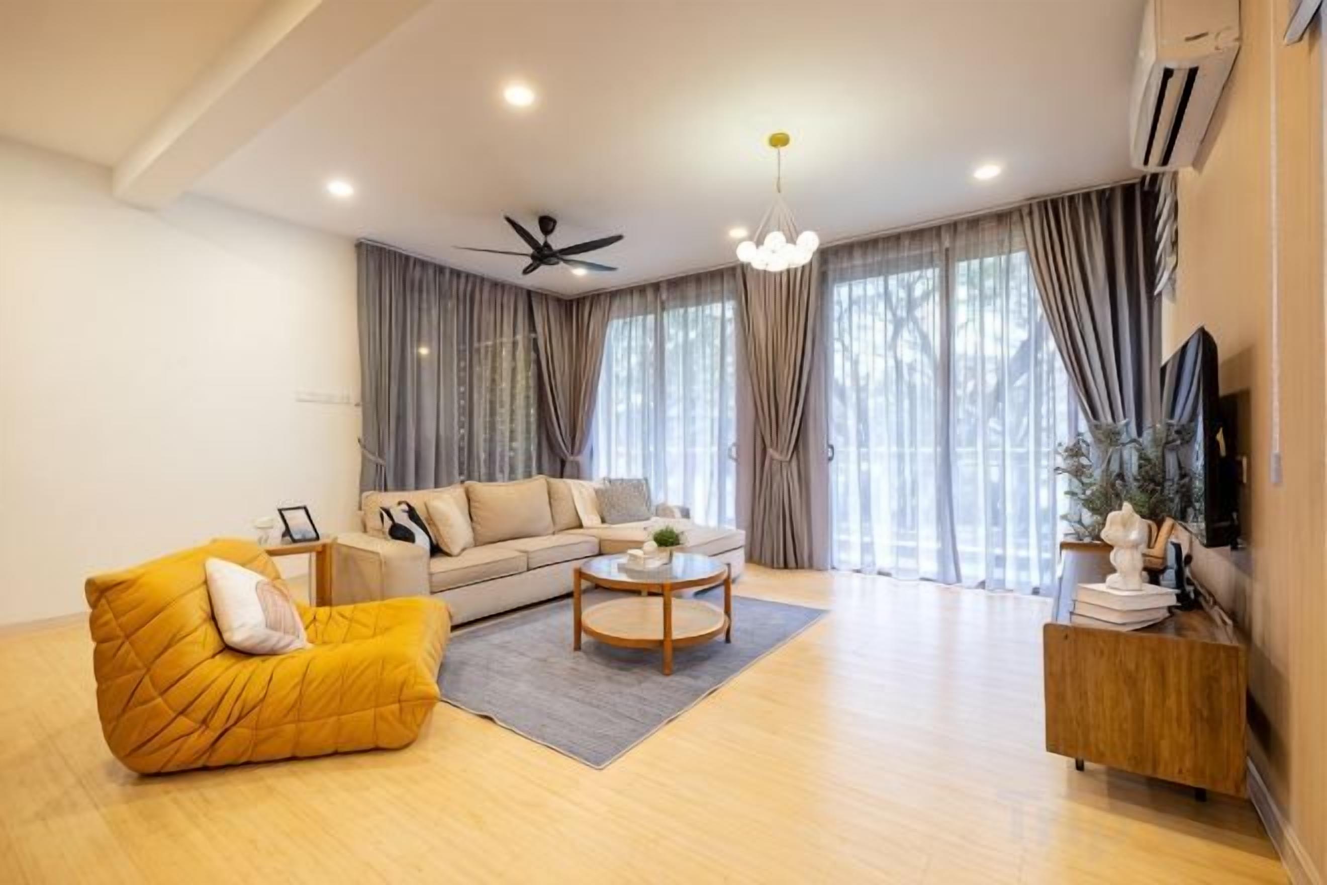 Un salon moderne avec un canapé, un fauteuil, une table basse et un téléviseur posé sur un meuble en bois.