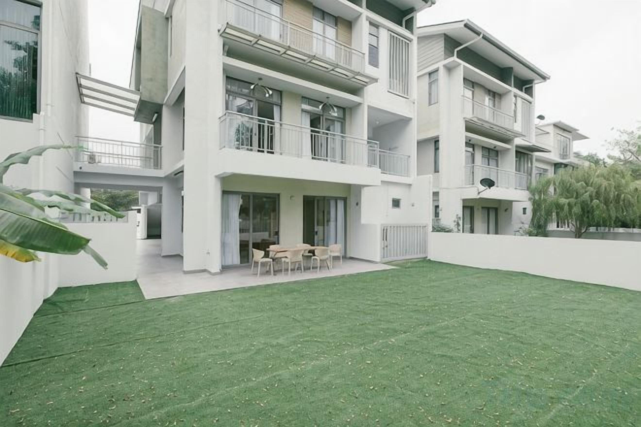 Un moderno edificio residencial de varios pisos con un césped cuidado y una zona de estar al aire libre.
