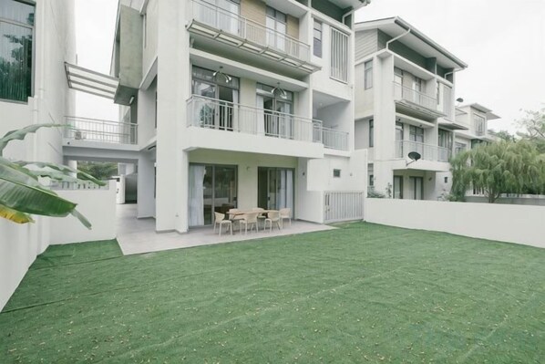 A modern multi-story residential building with a well-maintained lawn and outdoor seating area. - LAKE VILLA BY FEEL HOME (Putrajaya)