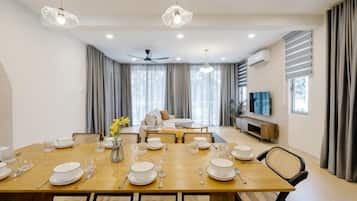 A dining area with a wooden table set for a meal, a ceiling fan, and a TV on the wall.