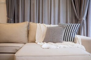 A beige sofa with patterned pillows and a white throw blanket. - LAKE VILLA BY FEEL HOME (Putrajaya)
