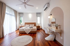 A bedroom with a bed, bedside tables, a desk, a chair, a round rug, a ceiling fan, and a large window. - LAKE VILLA BY FEEL HOME (Putrajaya)