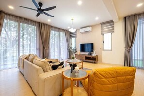 Un salon moderne avec un canapé, un fauteuil jaune, une table ronde et un ventilateur de plafond.