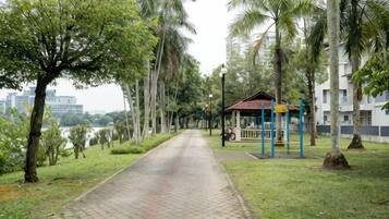 Un sendero pavimentado bordeado de árboles y una pequeña pérgola.