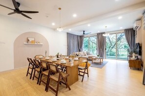 A spacious living area with a dining table, chairs, a sofa, and a balcony with a view. - LAKE VILLA BY FEEL HOME (Putrajaya)