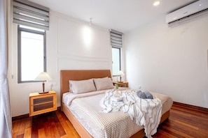 Een slaapkamer met een bed, nachtkastjes en een airconditioning.