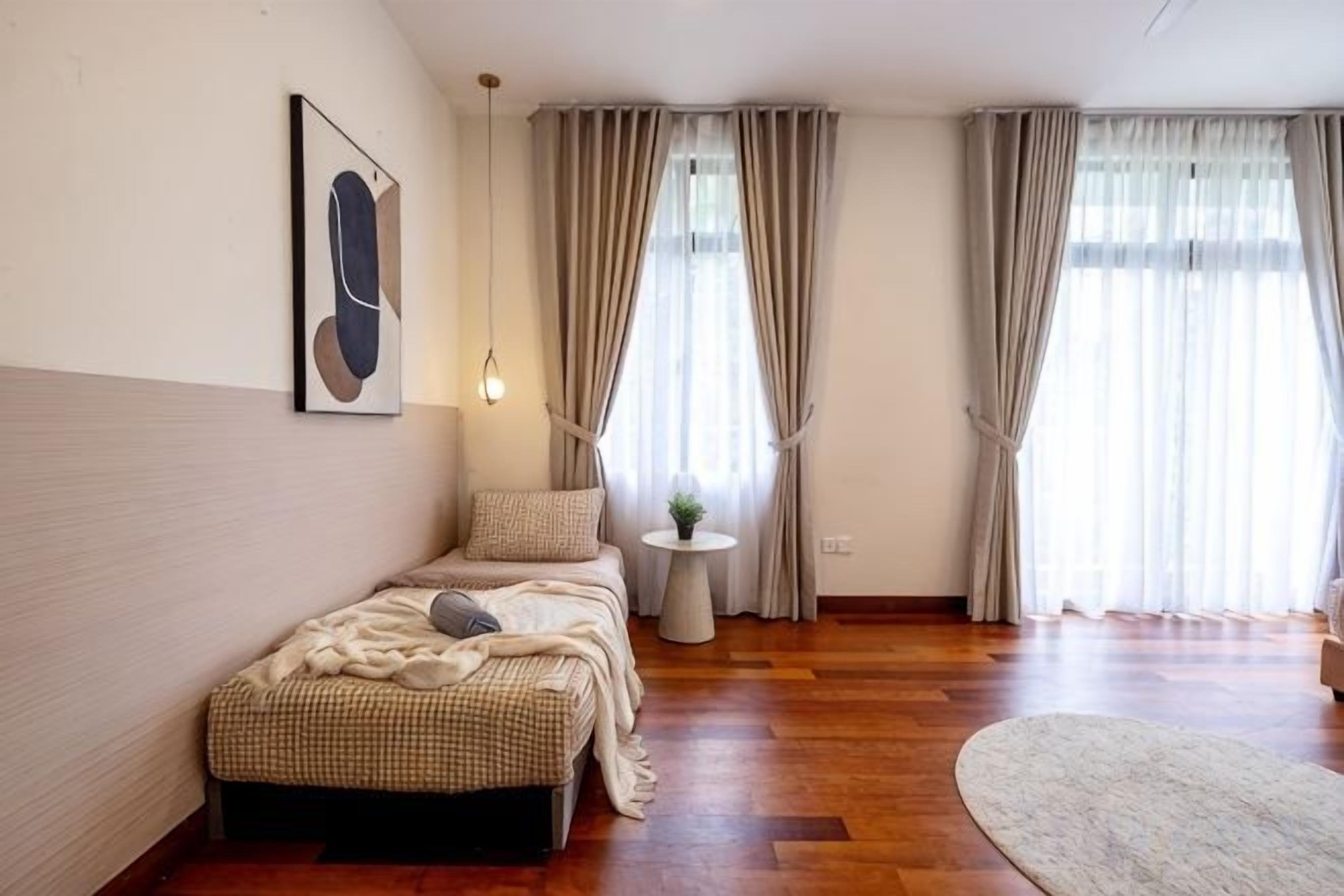 A bedroom with a bed, bedside table, and a window with curtains.