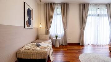 A bedroom with a bed, bedside table, and a window with curtains.