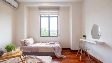 A bedroom with a bed, a desk, a chair, a window, and a mirror.