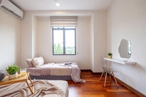 Een slaapkamer met een bed, een bureau, een stoel, een raam en een spiegel.