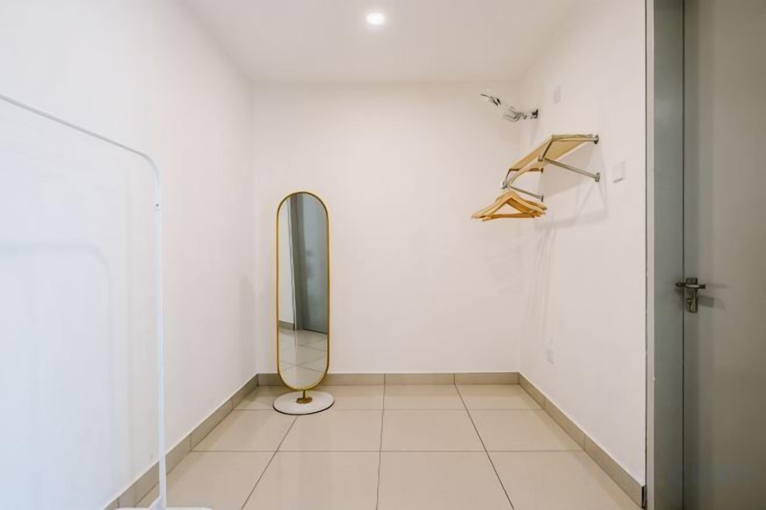 Une petite salle de bain vide, avec un miroir rond, un porte-serviettes et une porte.