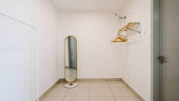 Une petite salle de bain vide, avec un miroir rond, un porte-serviettes et une porte.